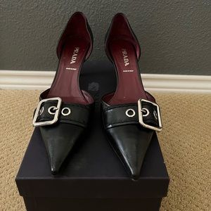 Prada black leather pumps with standout metal buckle.